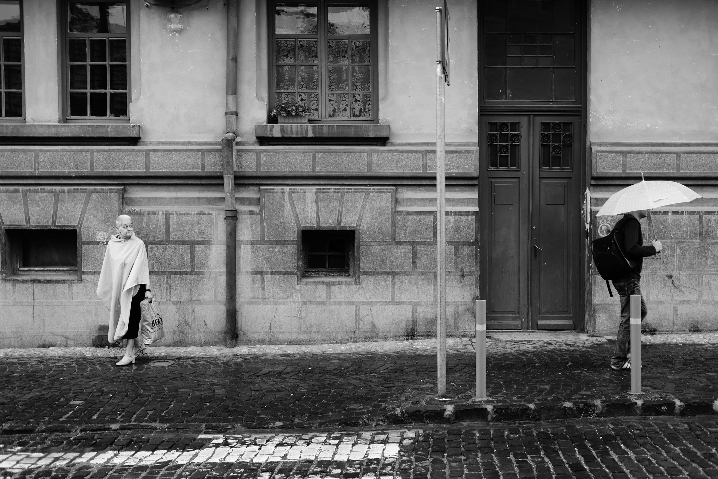 A woman walking past a man with an umbrella, Brasov